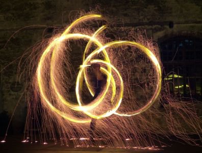 Goldener Funkenregen: leuchtende Sparkle-Poi-Kreise sprühen Funken in die Nacht.