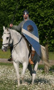 Berittener Krieger der Gruppe Claymore mit Kettenhemd und tropfenförmigem Normannenschild auf einem Schimmel.